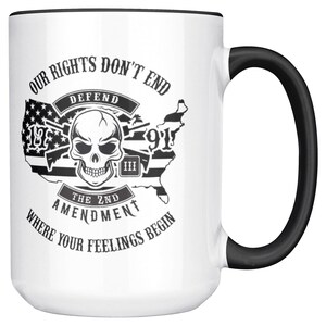 May include: White ceramic mug with a black handle and rim. The mug features a graphic with a skull, the American flag, and the text "OUR RIGHTS DON'T END, DEFEND THE 2ND AMENDMENT WHERE YOUR FEELINGS BEGIN."