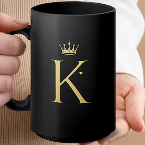 May include: Black ceramic mug with a gold crown and the letter K. The letter K has a small gold heart next to it.