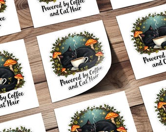 Könnte beinhalten: Eine schwarze Katze mit grünen Augen liegt in einem Kranz aus Blättern und Pilzen schlafend zusammengerollt. Die Katze hält eine dampfende Tasse Kaffee. Der Text "Powered by Coffee and Cat Hair" steht unter der Katze.