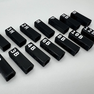 May include: A set of black plastic pencil holders with white numbers and letters printed on them. The numbers range from 2 to 12 and the letters are B and H.