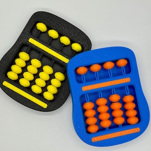 May include: Two brightly coloured abacuses. One is black with yellow beads, the other is blue with orange beads. The abacuses have a curved shape and are likely used for educational purposes, with the beads sliding along the rods.