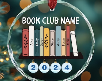 May include: A clear glass ornament with a colorful bookshelf design and the text "BOOK CLUB NAME". The bookshelf has seven books with names on the spines: Alice, Emily, Daron, Stacy, Ashly, Susan, and Daniel. There are four blue ornaments with the numbers 2024.