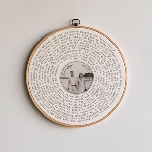 May include: A circular embroidery hoop featuring a black and white photograph of a couple. The photo is encircled by printed text. The text includes the names "Rod & Alyson" and the date "March 6, 2015".