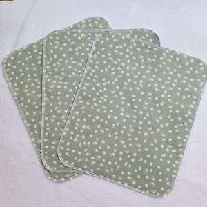 May include: Three green fabric cloths with a white polka dot pattern. The cloths have a stitched edge.