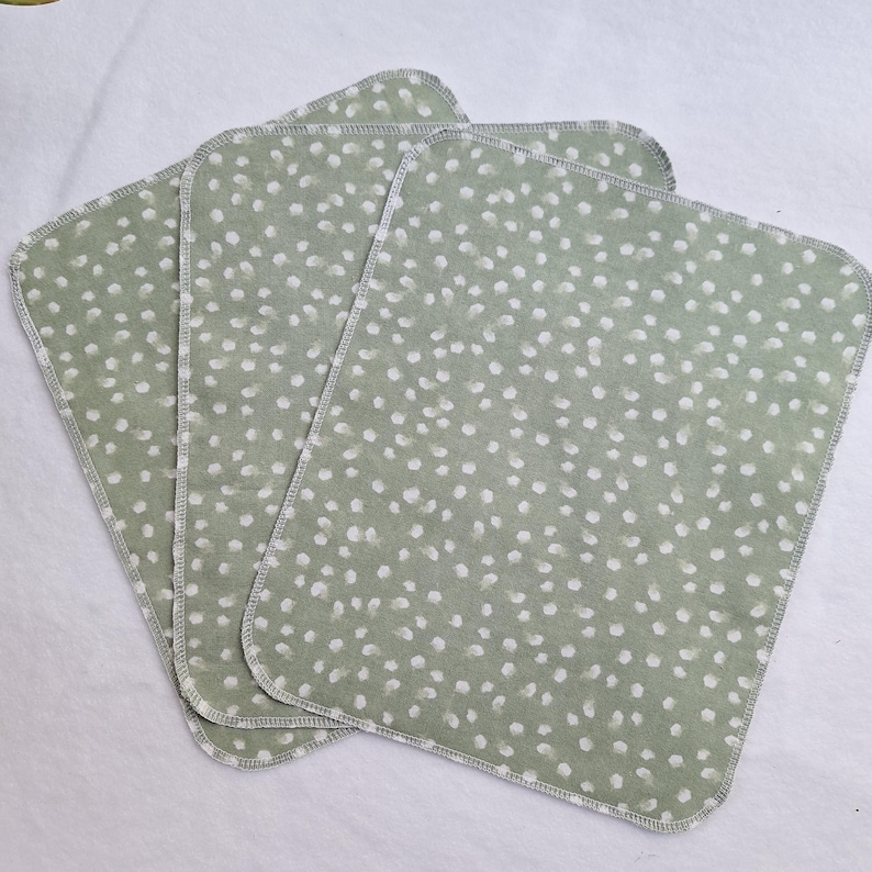 May include: Three green fabric cloths with a white polka dot pattern. The cloths have a stitched edge.