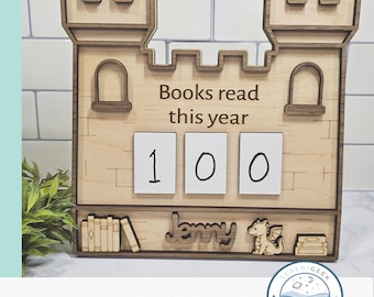 May include: Wooden castle-shaped book counter with the text "Books read this year" and the number "100" displayed. Includes the name "Jenny" and a dragon illustration. The design is laser-ready.