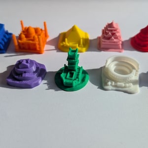 Puede incluir: Un conjunto de diez edificios en miniatura impresos en 3D de colores vivos, que incluyen una pagoda, una pirámide, un estadio y una mezquita. Los edificios son de diferentes tamaños y formas, y están hechos de una variedad de materiales.