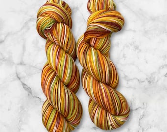 Peut inclure: Deux écheveaux de fil dans un motif de rayures multicolores. Le fil est un mélange de rouge, orange, jaune, vert et blanc.