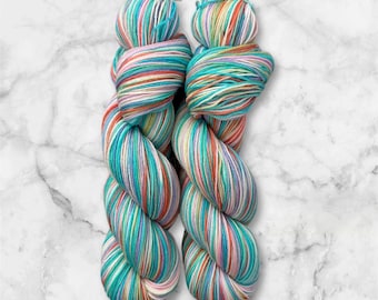 Peut inclure: Deux écheveaux de fil coloré avec des rayures turquoise, rose, orange, blanc et vert.