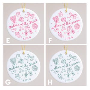 May include: White ceramic ornament with gold string, featuring pink or green illustrations and text. The text reads "Mother of the Bride" or "Mother of the Groom" with wedding-themed icons and the date "3.28.26".