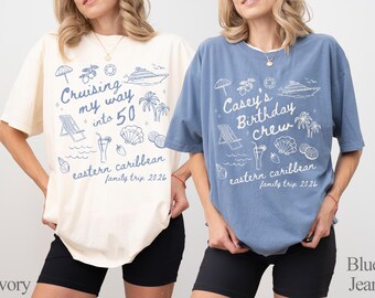 May include: Two short-sleeved t-shirts, one ivory and one blue, with a graphic design. The ivory shirt says "Cruising my way into 50" and the blue shirt says "Casey's Birthday Crew". Both shirts have a Caribbean theme.