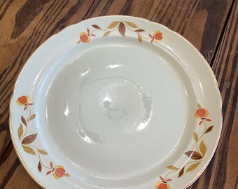 May include: Off-white ceramic plate with a scalloped edge and a gold rim. The plate is decorated with a floral pattern featuring orange and yellow flowers with brown and gold leaves. A vintage-style dish.