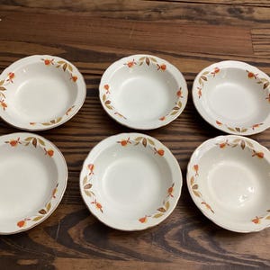 May include: Set of six white ceramic bowls with a brown and orange floral pattern. The bowls have a scalloped edge and are perfect for serving soup, cereal, or salad.