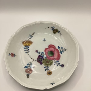 May include: White ceramic serving bowl with a scalloped edge, decorated with a floral pattern. The flowers are in shades of pink, yellow, purple, and green, with blue accents. The bowl has a delicate, elegant design.