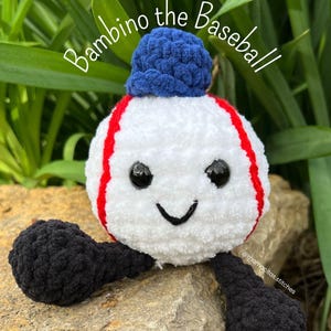 Puede incluir: Un personaje de béisbol de crochet con un sombrero azul, un cuerpo blanco, costuras rojas y brazos negros. El personaje está sentado en una roca con follaje verde en el fondo. El texto "Bambino the Baseball" está escrito encima del personaje. El texto "@mamacitas.stitches" está escrito debajo del personaje. El texto "Copyright 2023 Pattern and Design by Mamacitas Stitches" está escrito en la parte inferior de la imagen.
