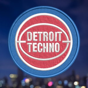 May include: Embroidered patch featuring a red and white circular design with the text "DETROIT TECHNO" in white. The patch has a blue border and is set against a blurred cityscape background.