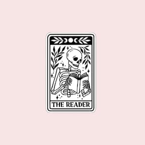May include: Black and white illustration of a skeleton reading a book, labeled "THE READER." The image is framed with botanical elements and celestial symbols. The background is a soft pink.