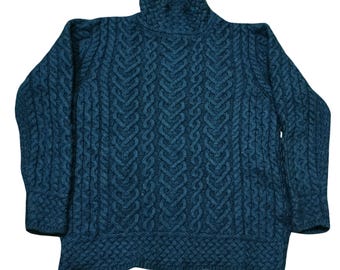 May include: A teal-colored turtleneck sweater with a cable-knit design. The sweater features a high, ribbed collar and a textured pattern across the body and sleeves. The knitwear has a classic, cozy appearance.