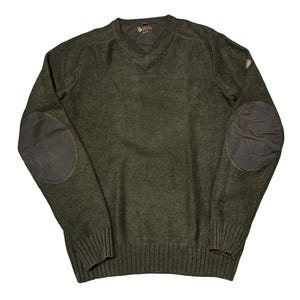 Puede incluir: Un suéter verde oscuro de cuello en V con parches de cuero en los codos. El suéter tiene una textura de punto de canalé y un pequeño logotipo en la parte delantera.