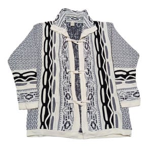 May include: A long-sleeved, cream-colored cardigan with a geometric pattern in black, gray, and white. The sweater features a collared neckline, toggle closures, and patterned sleeves. The overall design is a mix of abstract and tribal motifs.