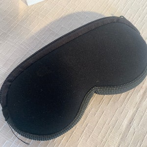 May include: A black sleep mask with a soft, padded interior and a contoured shape to fit comfortably over the eyes.