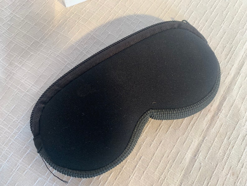 May include: A black sleep mask with a soft, padded interior and a contoured shape to fit comfortably over the eyes.