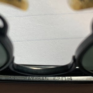 May include: Close-up of the black Ray-Ban 62□14 sunglasses frame.