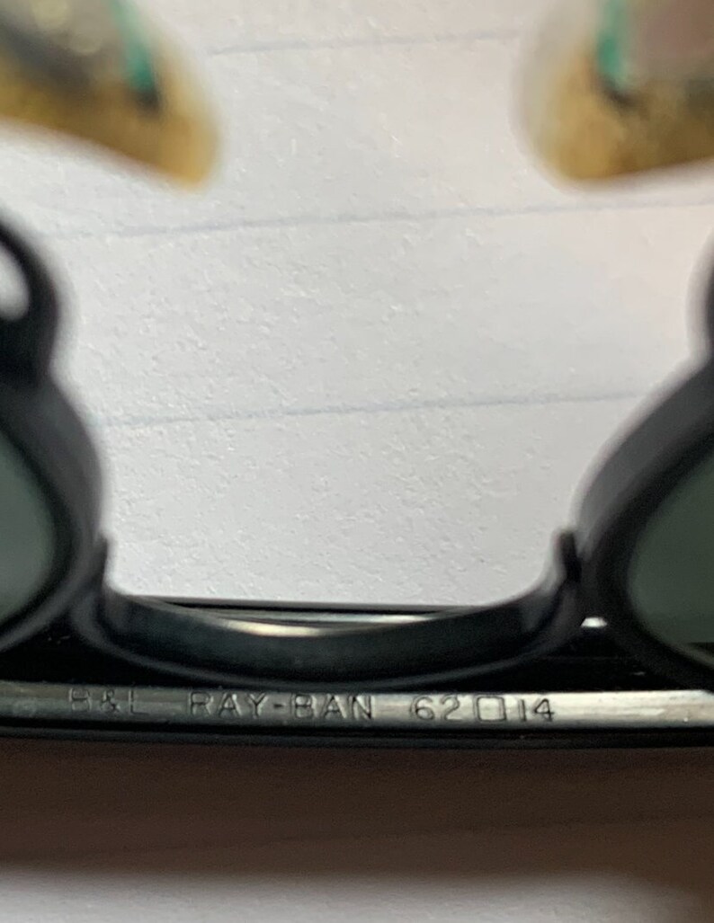 May include: Close-up of the black Ray-Ban 62□14 sunglasses frame.