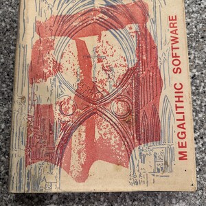 May include: A vintage book cover with a red and blue illustration of an arched doorway. The text "MEGALITHIC SOFTWARE" is printed on the right side of the cover.