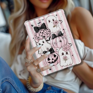 May include: A tablet case with a pink and white striped design, decorated with Halloween illustrations. The design includes pink pumpkins with black bows, ghosts, spiderwebs, and bats. The case is held in a person's hand.