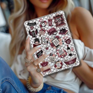 May include: A white tablet case with a black grid pattern and various burgundy and white stickers. Stickers include text like "Library Lust", "Dear Diary He Ruined Me", and "My TBR Filthy". The case is held by a person.