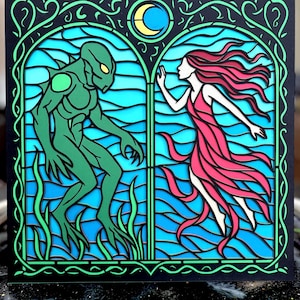 May include: A layered art piece depicting a scene with a green creature and a woman in a red dress. The artwork is framed by a black border with green and blue accents, and a crescent moon.