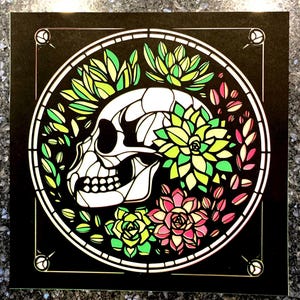 May include: A black and white skull with green and pink succulents surrounding it. The skull and succulents are in a circle with a black background.