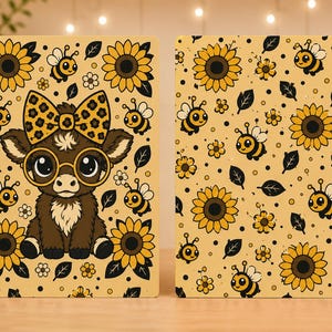 May include: A disc-bound notebook featuring two covers with a yellow background, sunflowers, and bees. The front cover displays a brown calf wearing round glasses and a leopard-print bow, while the back cover shows a repeating pattern of bees and sunflowers.