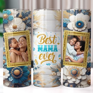 May include: Two stainless steel tumblers with a white background and floral design. The tumblers feature a gold frame with a photo of two people hugging. The text "Best Mama Ever" is written in gold lettering on the tumbler.