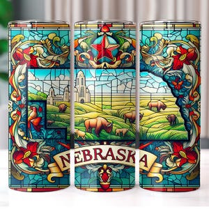 Może przedstawiać: Trzy kubki ze stali nierdzewnej z kolorowym wzorem witrażowym przedstawiającym zarys stanu Nebraska, czerwoną gwiazdę i różne motywy kwiatowe i zwierzęce. Kubki są ozdobione napisem "Nebraska" na banerze.