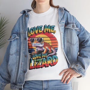May include: White t-shirt with a colorful graphic of a lizard wearing sunglasses and the text "Love Me, Love My Lizard".
