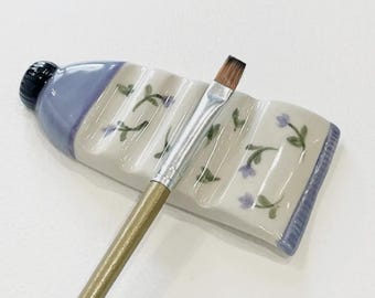 Ręcznie robiona ceramiczna podstawka pod pędzel: tubka z farbą i drobnymi kwiatowymi akcentami