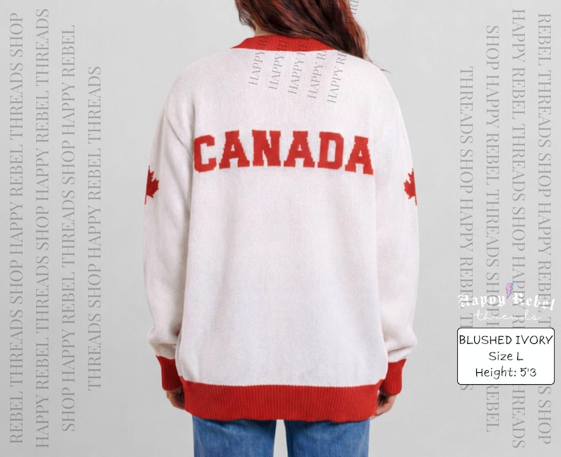 Może przedstawiać: Sweter z dzianiny w kolorze kości słoniowej z napisem CANADA wyhaftowanym pogrubionymi czerwonymi literami na plecach. Odzież posiada czerwone wykończenia przy kołnierzu, mankietach i u dołu oraz czerwony liść klonu na każdym rękawie. Widoczny jest tekst BLUSHED IVORY, Size L, Height: 5'3.