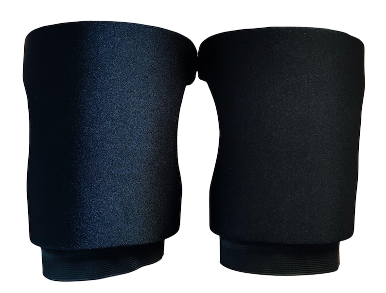 May include: A pair of solid black knee pads featuring a contoured, flexible design with a smooth, matte exterior finish. These protective sleeves are constructed with a thick, padded central section and reinforced elastic bands at the top and bottom.
