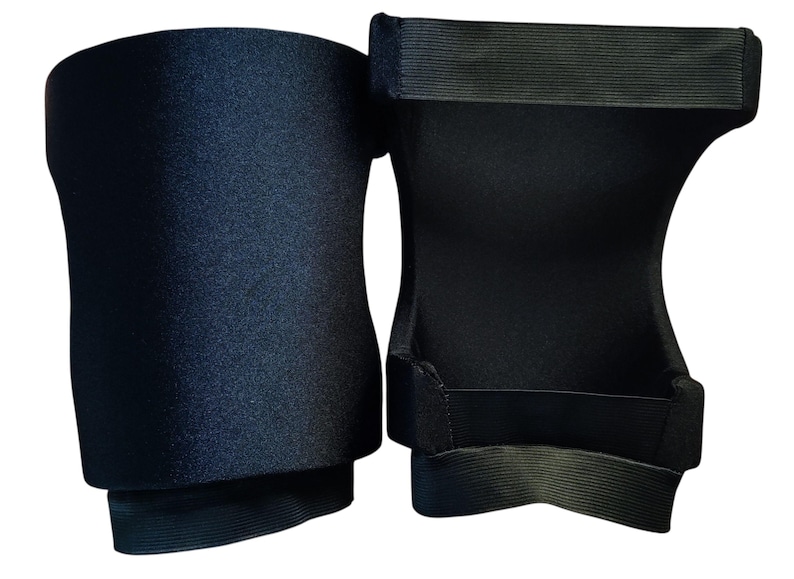 May include: A pair of black knee pads featuring a smooth, solid-colored exterior fabric and a contoured shape. The interior side displays a structured design with wide, horizontal elastic bands at the top and bottom edges for secure placement.