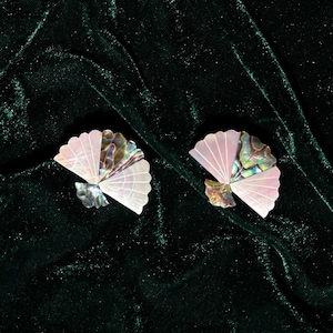 Peut inclure: Deux éventails en coquille nacrée rose et verte sur un fond de velours vert foncé.