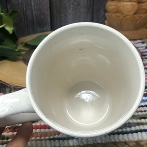 May include: White ceramic mug with a speckled finish. The mug is empty and has a handle.