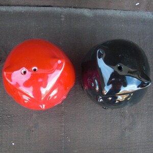 Peut inclure: Deux sali&egrave;res et poivri&egrave;res en c&eacute;ramique en forme de hiboux. Le hibou de gauche est rouge et le hibou de droite est noir.