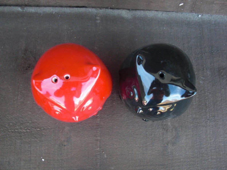 Peut inclure: Deux sali&egrave;res et poivri&egrave;res en c&eacute;ramique en forme de hiboux. Le hibou de gauche est rouge et le hibou de droite est noir.