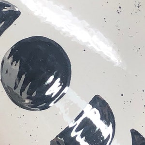 May include: A white ceramic mug with a black and white moon design. The moon design is painted in a glossy finish.