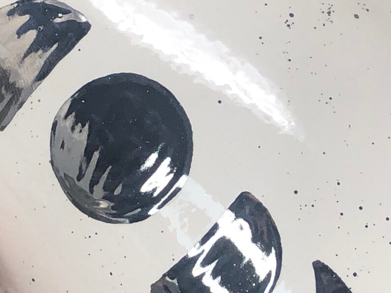 May include: A white ceramic mug with a black and white moon design. The moon design is painted in a glossy finish.