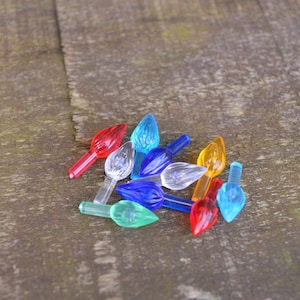 Może przedstawiać: Zestaw kolorowych plastikowych końcówek do żarówek choinkowych w kolorze czerwonym, niebieskim, zielonym, przezroczystym i pomarańczowym.