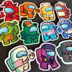 May include: A collection of eleven die-cut stickers featuring various characters from the game Among Us, each depicted in different colors, outfits, and accessories, including hats, uniforms, and casual clothing, all with a light blue visor.