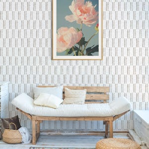 Pu&ograve; includere: Una stampa floreale incorniciata con due grandi fiori di peonia rosa chiaro su uno sfondo azzurro. La stampa con cornice dorata &egrave; appesa sopra un futon di legno con cuscini e cuscini bianchi. Un cesto intrecciato e un tappeto sono in primo piano.
